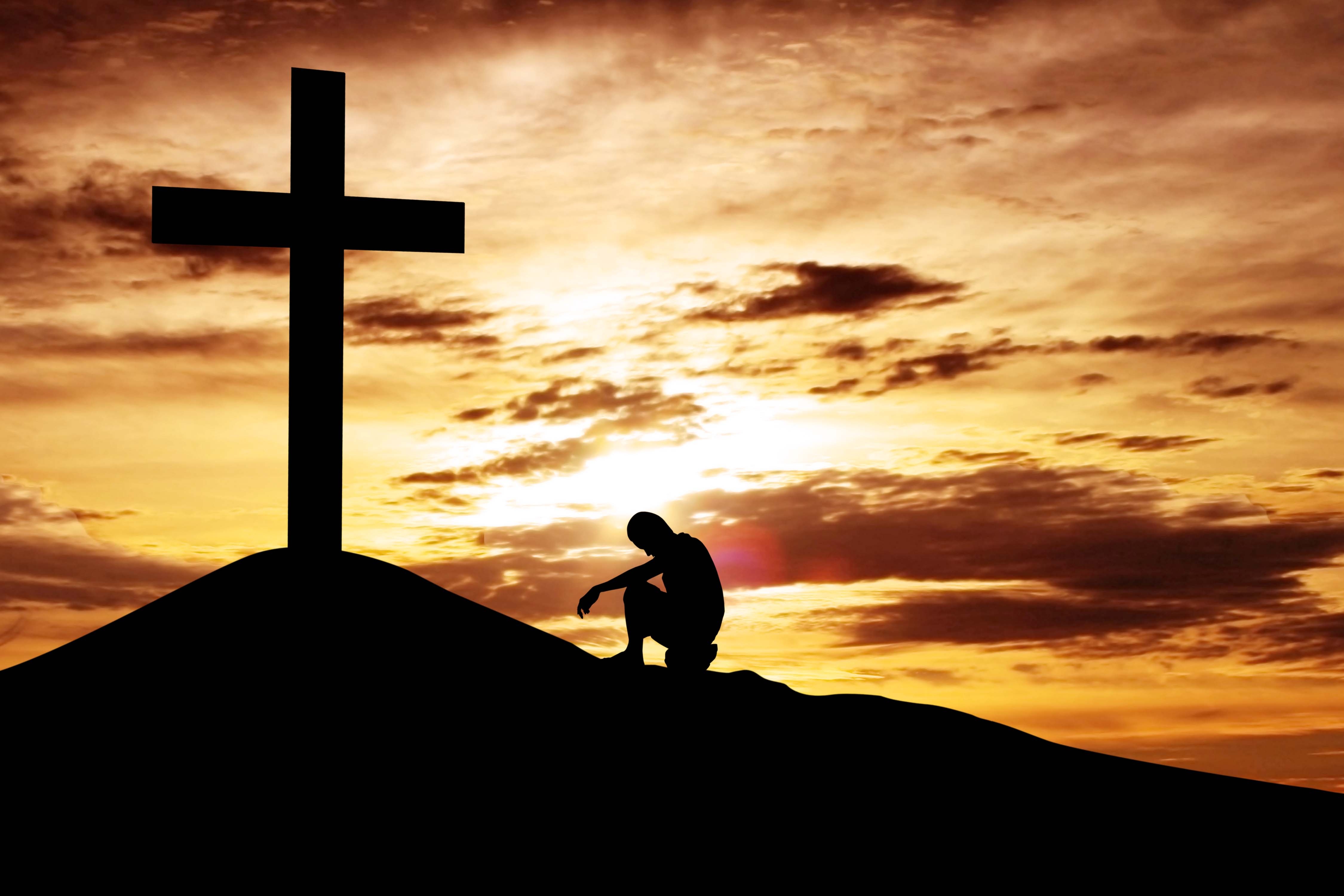 Man sitting desperately under the cross
